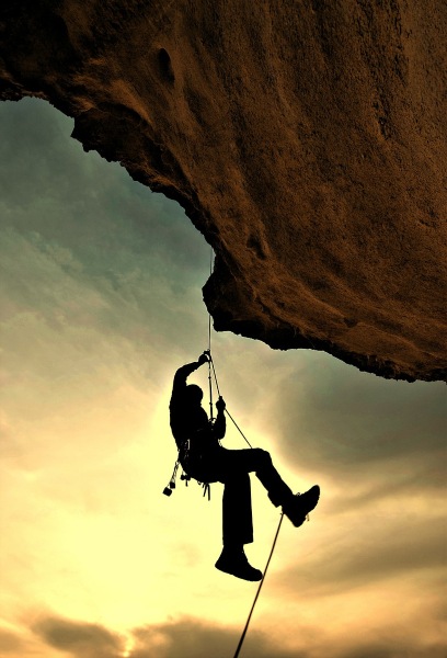escalador trepando por una pared al atardecer