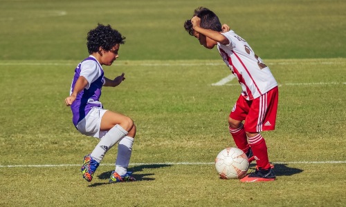 dos niños haciendo un regate mientras juegan al fútbol
