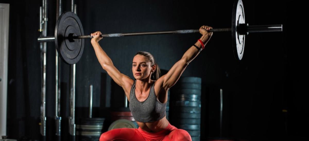 Mujer ejercitándose con pesas en un gimnasio.