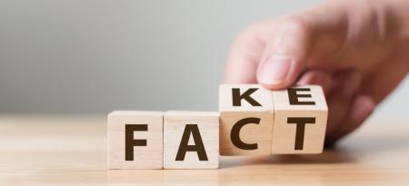 Dados de madera con las letras fact y fake (hecho y falso en inglés).